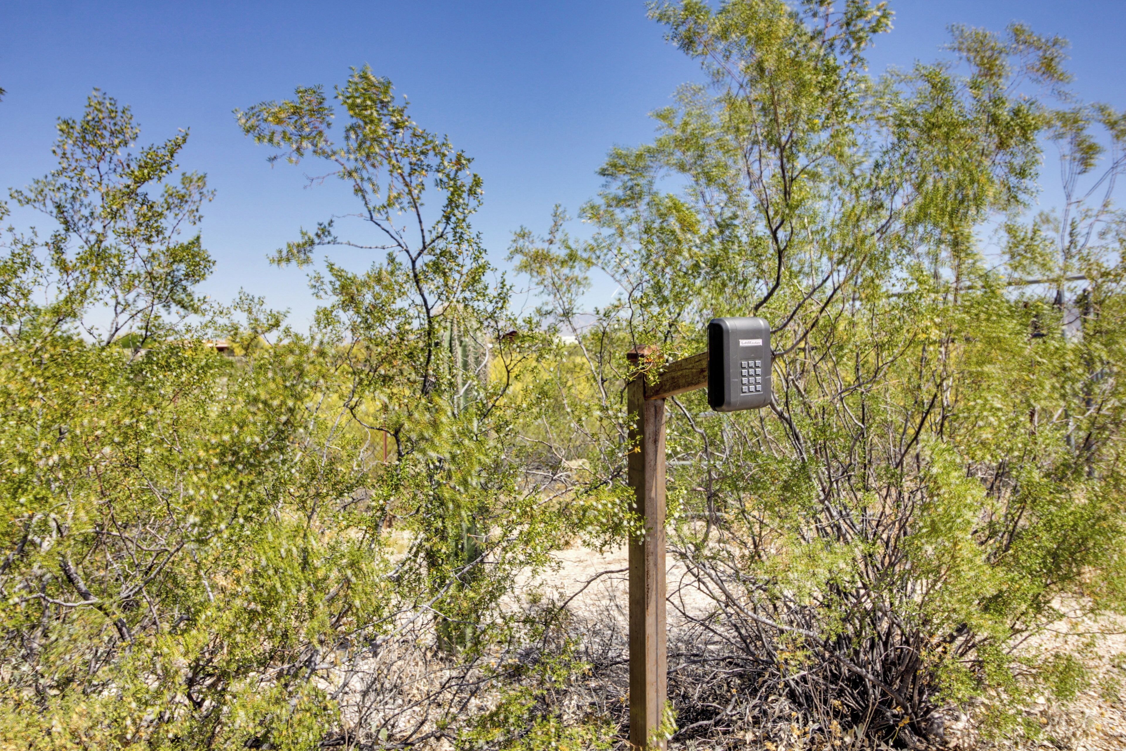 A wooden signpost with a digital display in a natural, bushy landscape.