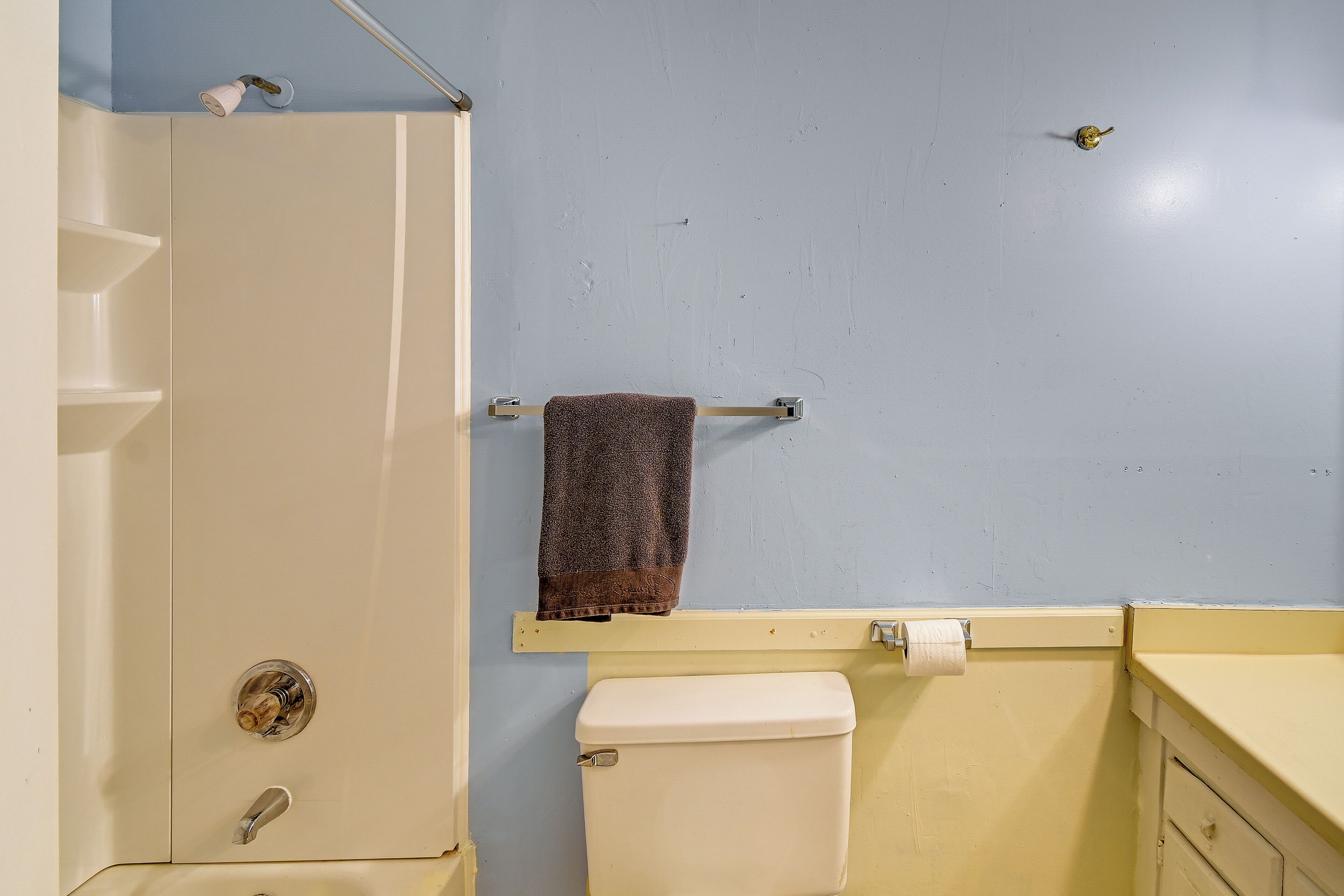 Een badkamer met een wit toilet, een handdoekrek met een handdoek en een douchedeur.