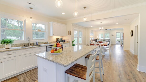 A spacious kitchen with white cabinetry, a central island with seating, and pendant lighting. - New Bern Vacation Rental on Farm w/ Fire Pit! (New Bern)