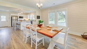 A spacious kitchen with white cabinetry, a wooden dining table set for six, and a large window providing natural light. - New Bern Vacation Rental on Farm w/ Fire Pit! (New Bern)
