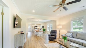 A spacious living area with a wooden floor, a sofa, a coffee table, and a ceiling fan. - New Bern Vacation Rental on Farm w/ Fire Pit! (New Bern)