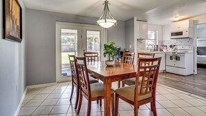 A dining area with a wooden table and chairs, a chandelier, and a kitchen in the background. - Orlando Health Access Pet-friendly Lakeland Gem (Lakeland)