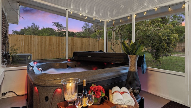 A hot tub with candles, wine glasses, and towels, set in a covered outdoor area with string lights. - Orlando Health Access Pet-friendly Lakeland Gem (Lakeland)
