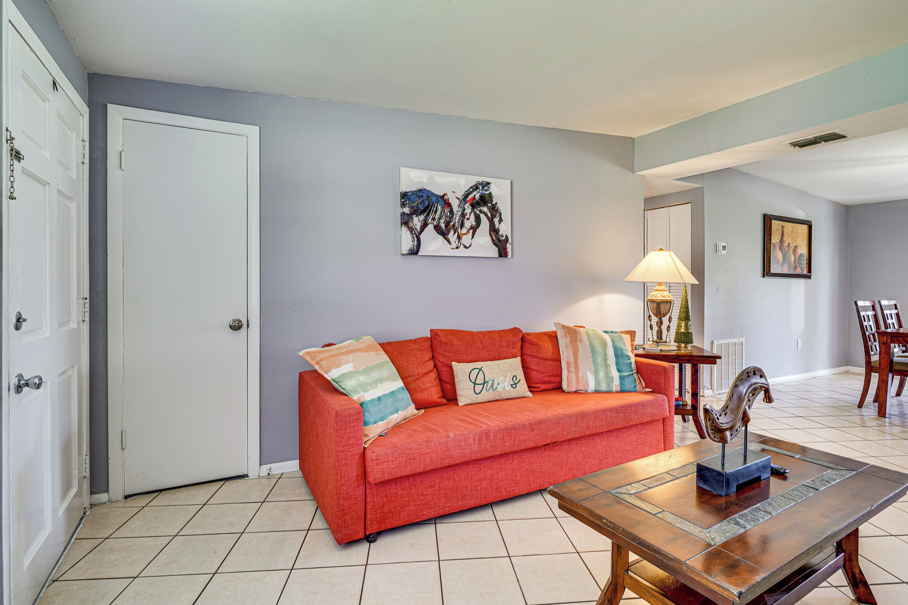 A living room with a red sofa, a coffee table, and a painting on the wall.