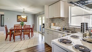 A modern kitchen with white cabinets, a gas stove, and a large window. - Orlando Health Access Pet-friendly Lakeland Gem (Lakeland)