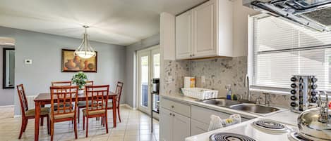 A modern kitchen with white cabinets, a gas stove, and a large window.