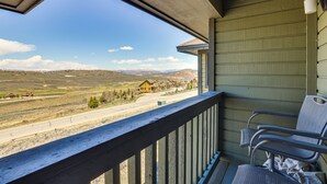 Un balcon donnant sur un paysage rural, une chaise et un luminaire.