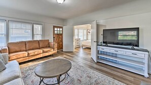 A spacious living room with a brown leather sofa, a round coffee table, and a large flat-screen TV on a white entertainment unit. - Walk to Poway Farmers' Market: Family Retreat! (Poway)