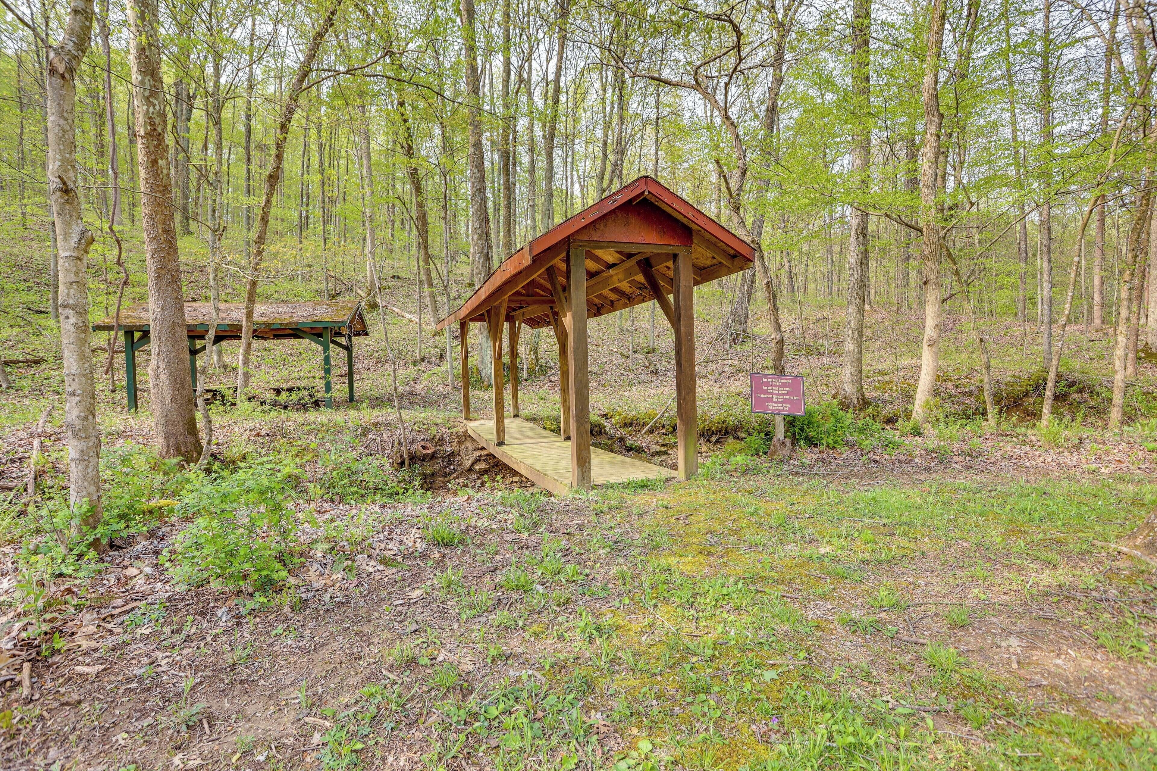 Ein hölzerner Pavillon in bewaldeter Landschaft mit einem Picknicktisch in der Nähe.