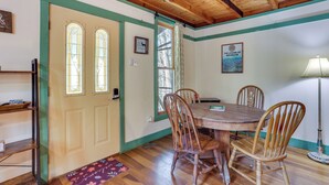 A dining area with a wooden table and chairs, a door with stained glass windows, and a wall-mounted sign.