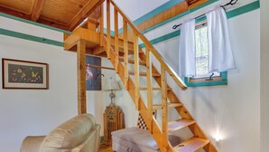 A wooden staircase with a cushioned bench at the bottom, a lamp, and a framed botanical illustration on the wall.