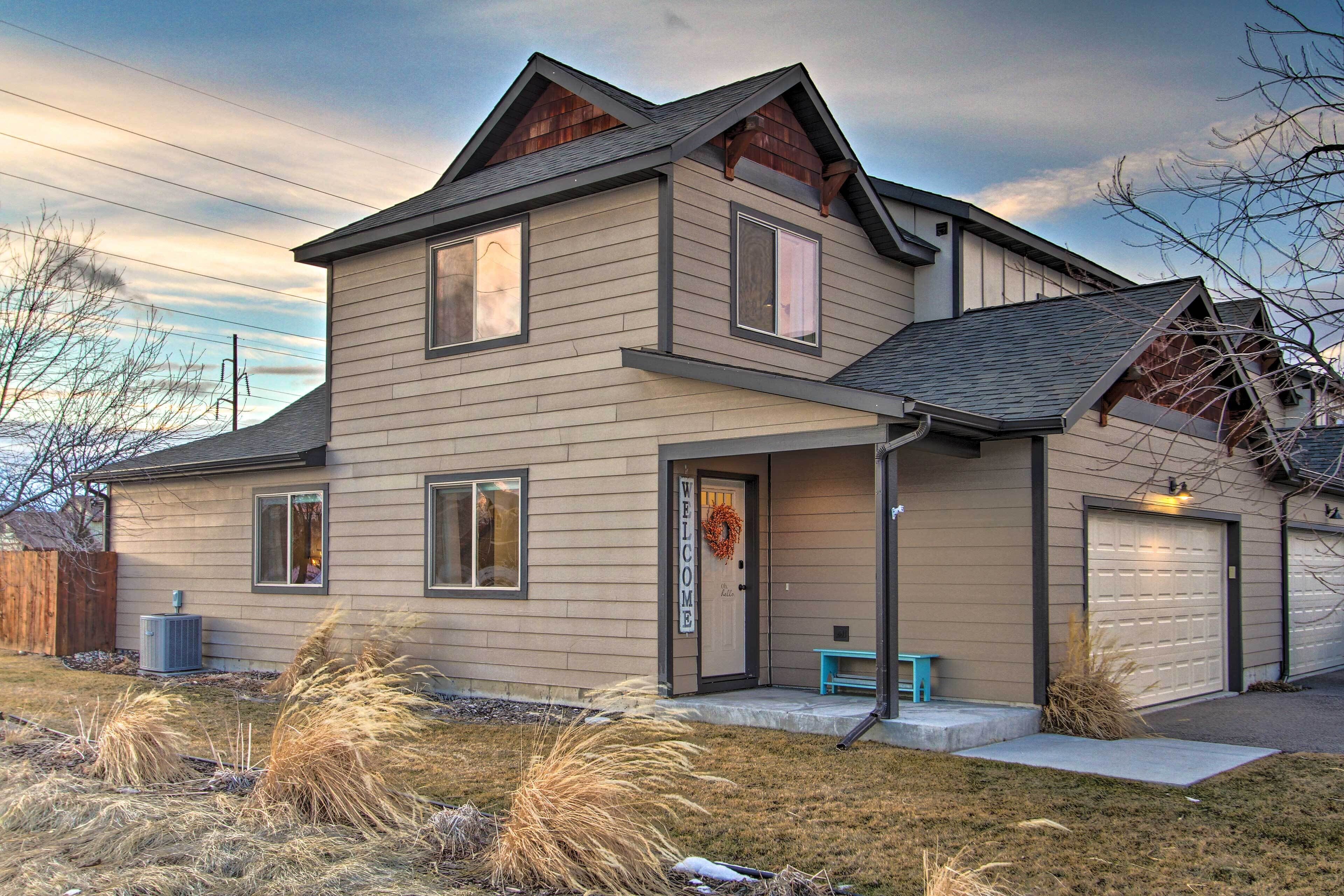 A two-story house with a front porch, a welcome sign, and a garage.