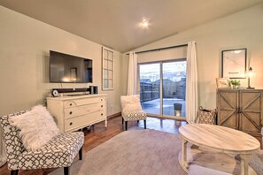 A living room with a TV, a white dresser, a patterned sofa, a coffee table, and a large window with a view. - Townhome w/ Private Hot Tub, 8 Mi to Downtown (Bozeman)