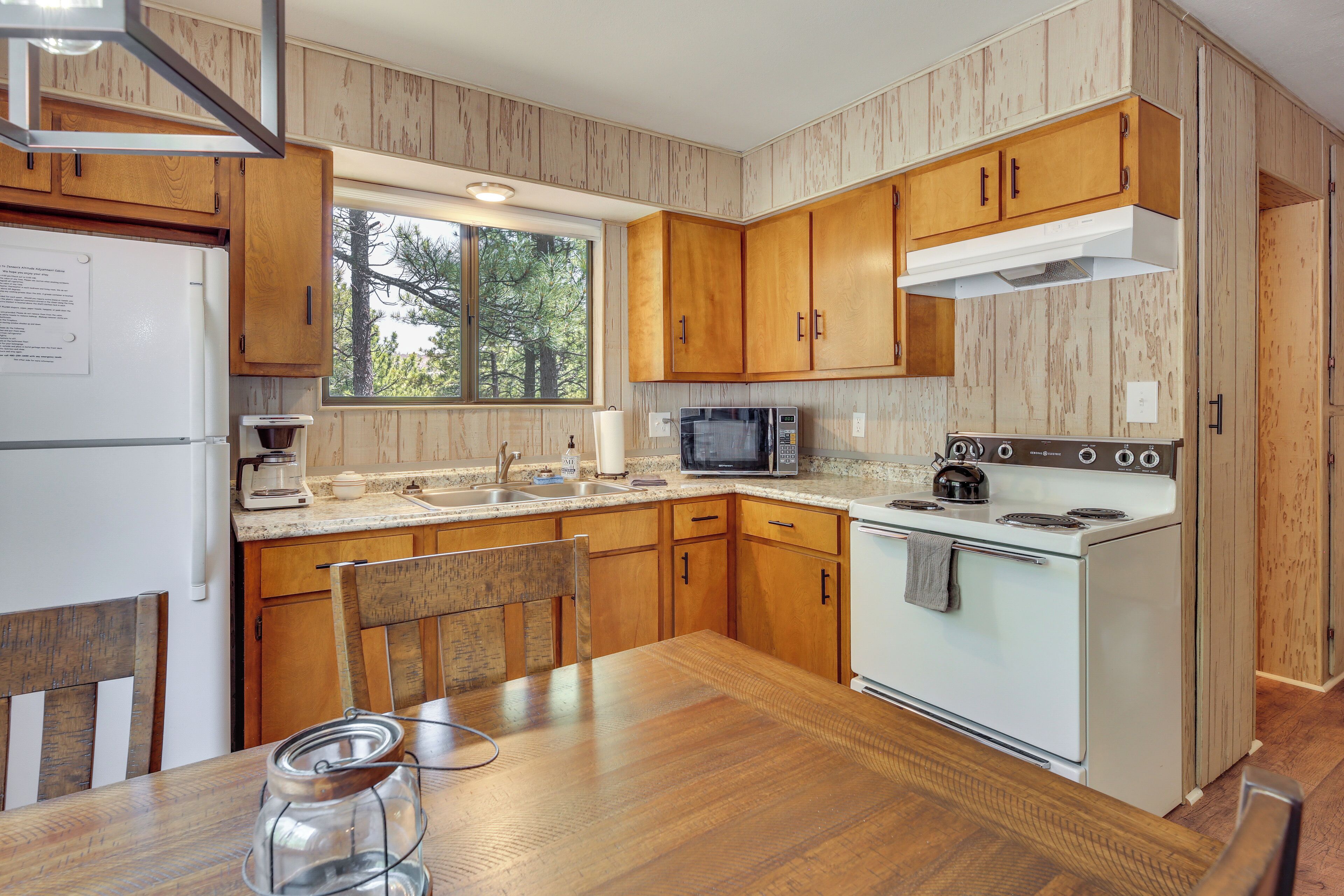 A kitchen with wooden cabinets, a stove, a microwave, and a dining table.