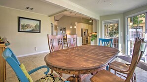 A dining area with a wooden table and chairs, a ceiling fan, and a kitchen in the background. - Glendale Oasis w/ Fenced Yard & Private Pool! (Glendale)