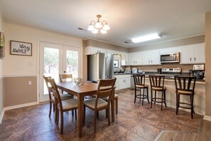 A spacious kitchen with a dining area, featuring a central island, white cabinets, and a large refrigerator. - Decatur Vacation Rental Retreat w/ Private Yard! (Decatur)