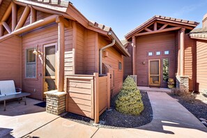 A wooden cabin with a porch, a bench, and a small stone wall. - Luxe Resort Cabin w/ Deck: Hike, Swim, Relax! (Show Low)