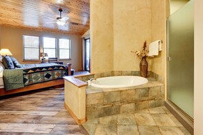 A bedroom with a bed, a nightstand, a lamp, and a window. - Luxe Resort Cabin w/ Deck: Hike, Swim, Relax! (Show Low)