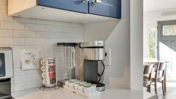 A kitchen with a coffee maker, a vent fan, and a coffee pod dispenser.