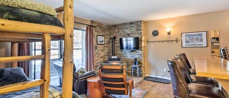 Una habitación acogedora con literas, una mesa de comedor de madera, un televisor y una chimenea.