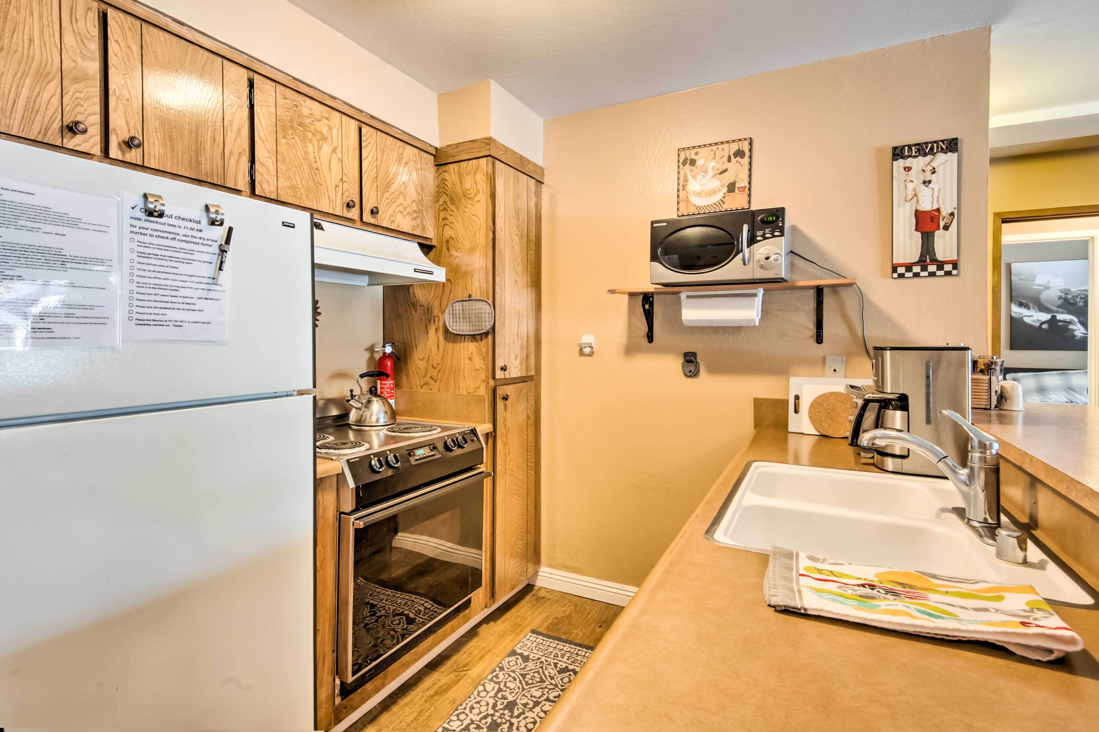 A compact kitchen with wooden cabinets, a built-in oven, a microwave, and a sink.
