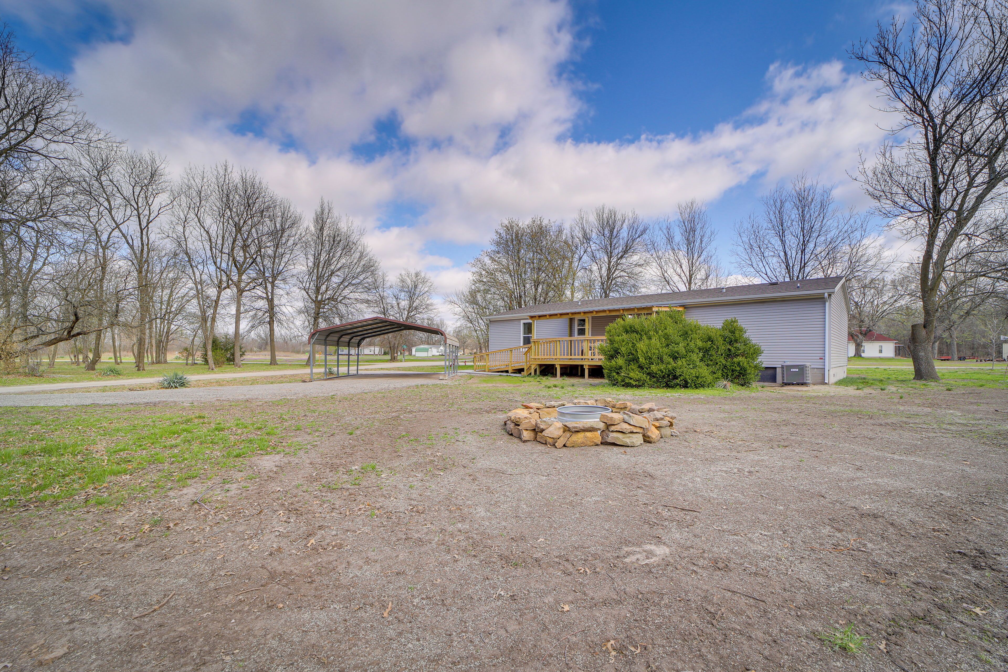 A residential property with a stone fire pit, a covered patio, and a two-story house with a porch.