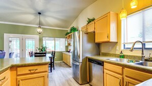 A kitchen with wooden cabinets, a stainless steel refrigerator, a dishwasher, and a granite countertop.