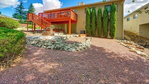 A modern house with a stone patio, a wooden staircase, and a view of the surrounding landscape.