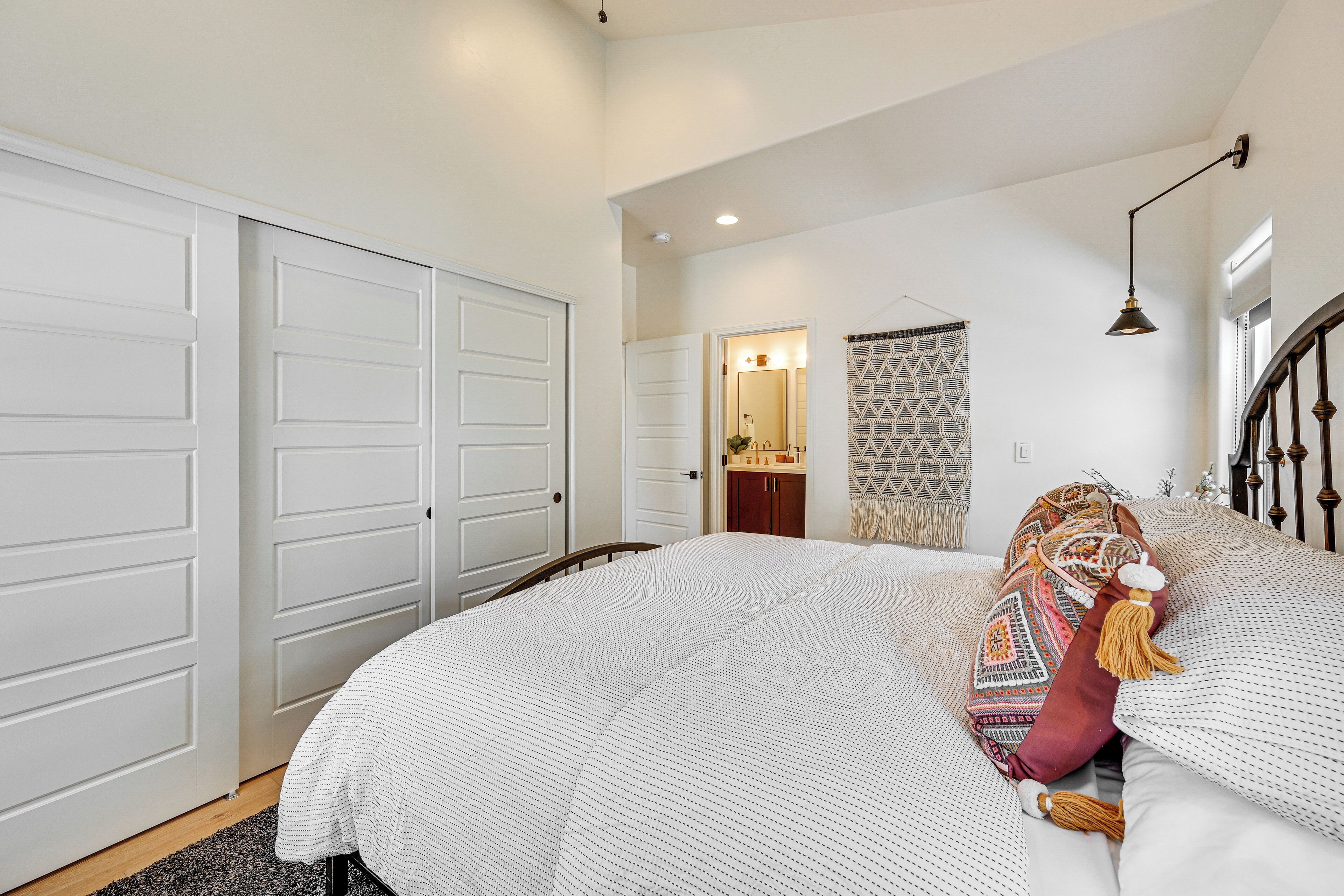 A bedroom with a large bed, a wardrobe, a mirror, and a patterned curtain.