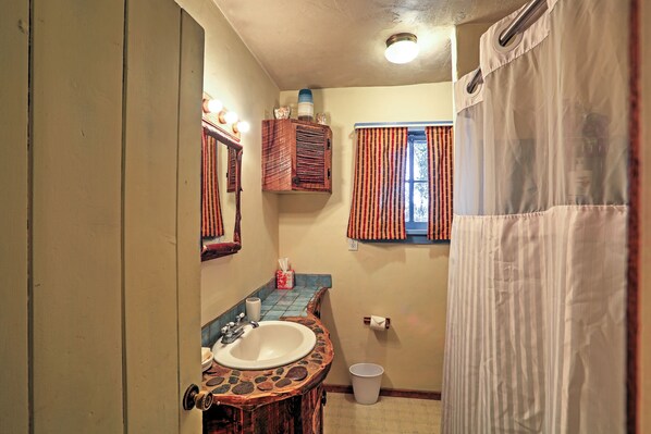 A bathroom with a stone sink, a mirror, a towel rack, and a shower curtain. - Quiet Durango Farmhouse w/ Beautiful Yard & Gazebo (Durango)