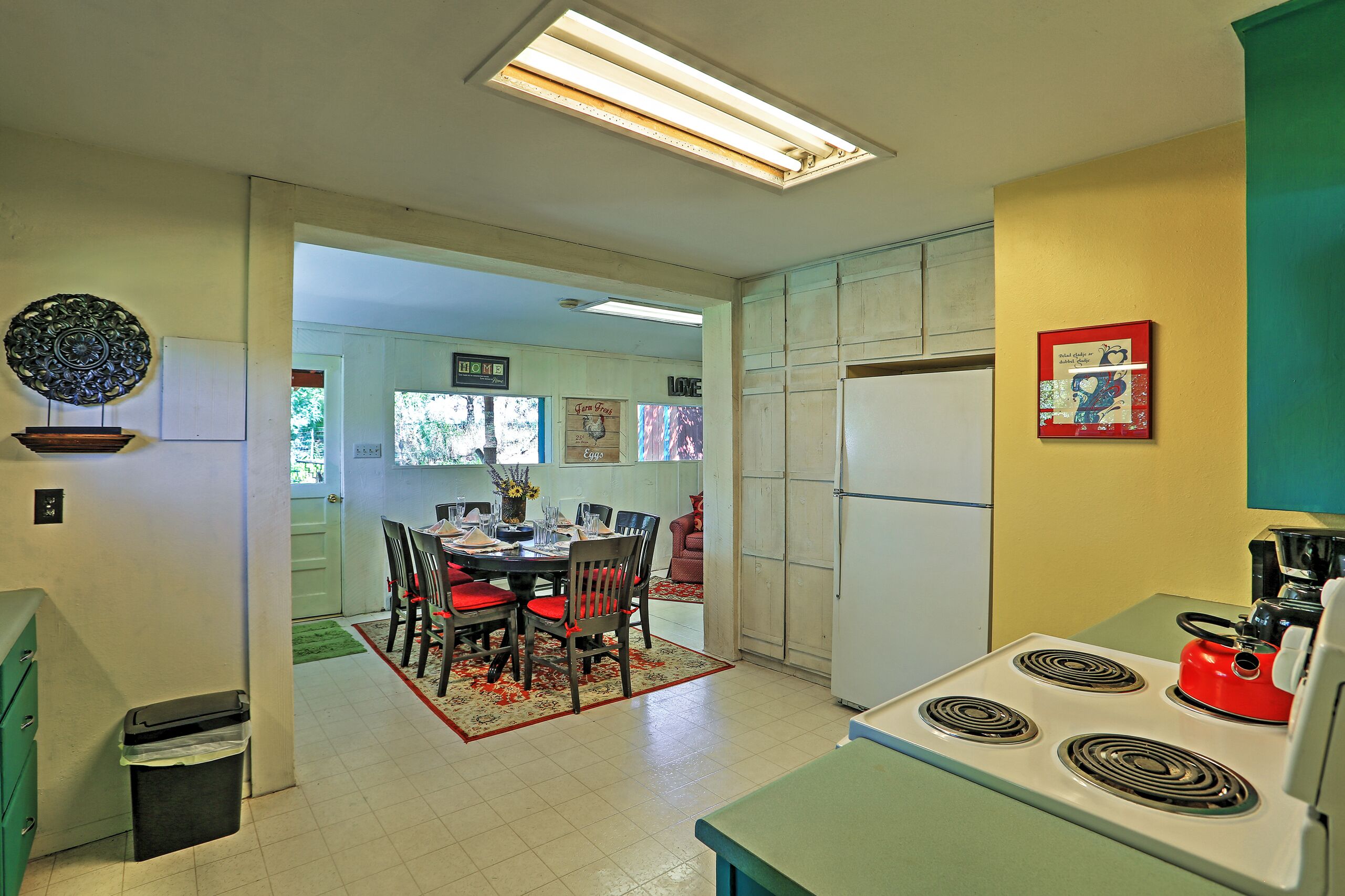 Una cocina con estufa, refrigerador y comedor con sillas y mesa.