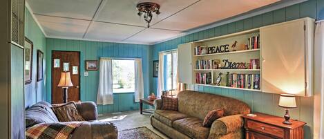 A cozy living room with two sofas, a wooden side table, and a bookshelf filled with books.