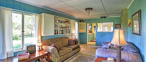 A cozy living room with a vintage sofa, a wooden coffee table, and a bookshelf filled with books.