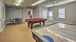 A pool table in a room with a ceiling fan, a pool table, and a door leading to another room. - Stokesdale Vacation Rental w/ Game Room! (Stokesdale)