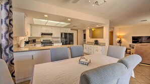 A modern kitchen with white cabinets, a central island, and a dining area with a table and chairs.