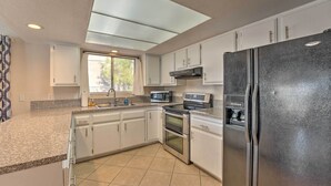A modern kitchen with white cabinets, a black refrigerator, a microwave, and an oven.