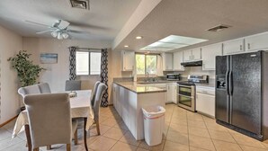 A modern kitchen with a central island, white cabinetry, stainless steel appliances, and a ceiling fan.