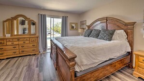 A bedroom with a wooden bed, a dresser, a mirror, and a window with curtains.