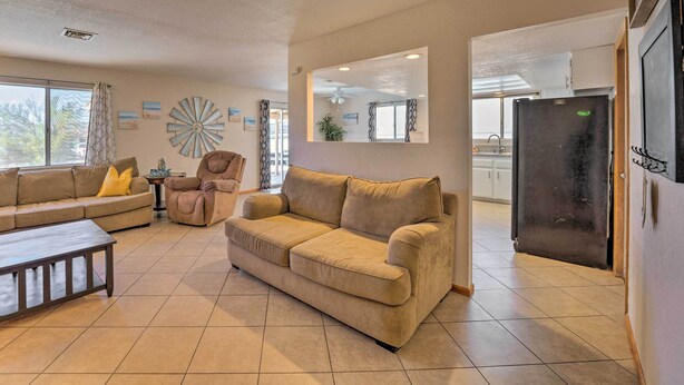 A living room with a beige sofa, a coffee table, a chair, and a large mirror.