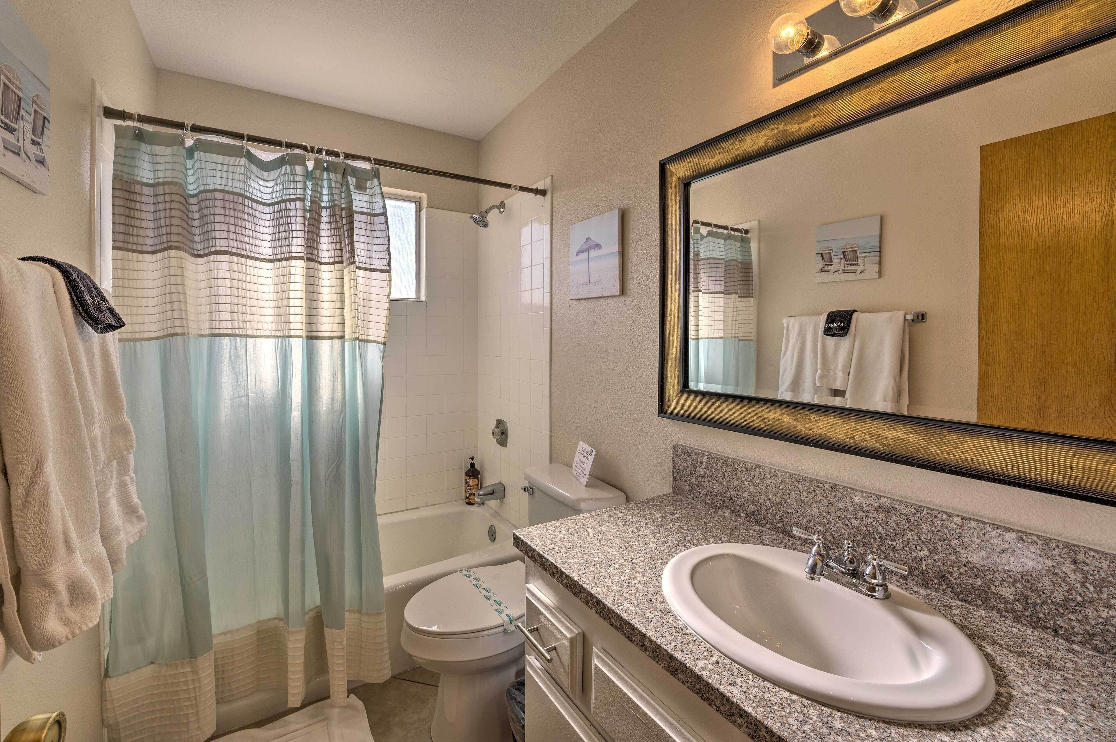 A bathroom with a shower curtain, a toilet, a sink, and a mirror.