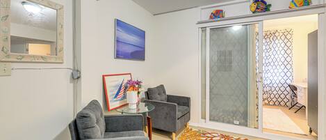 A living room with grey sofas, a glass coffee table, a framed picture, and a colorful rug.