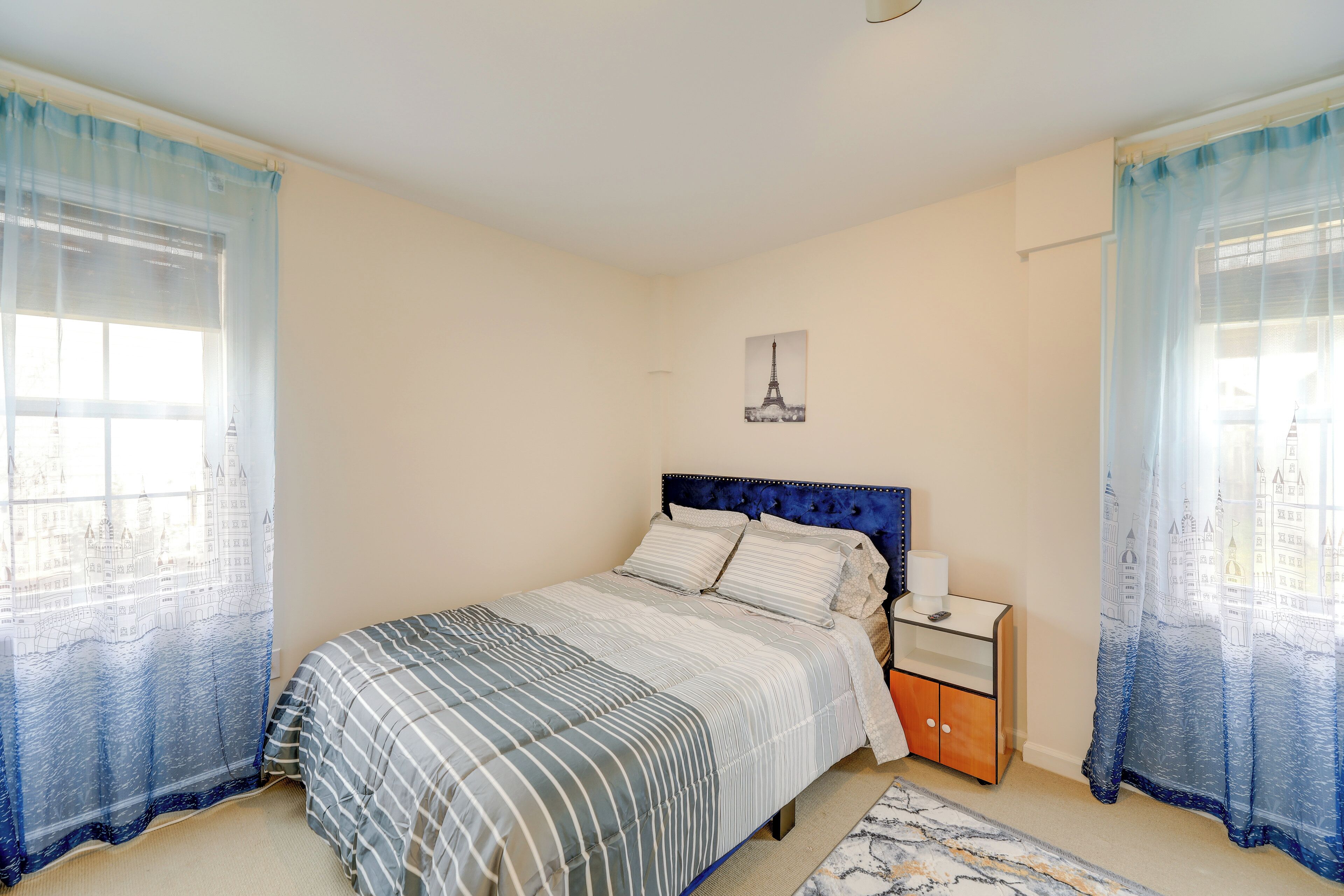 Een slaapkamer met een bed, nachtkastje en gordijnen.