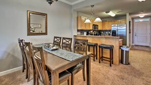 A dining area with a wooden table and chairs, a kitchen with wooden cabinets and stainless steel appliances, and a hallway with a door. - Sevierville Resort Retreat ~ 2 Mi to Pigeon Forge! (Sevierville)