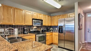 A kitchen with wooden cabinets, a stainless steel refrigerator, a microwave, an oven, and granite countertops. - Sevierville Resort Retreat ~ 2 Mi to Pigeon Forge! (Sevierville)