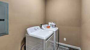 A laundry area with a front-loading washer and dryer, a utility meter, and laundry supplies on a small table. - Mt Juliet Getaway w/ Yard: 22 Mi to Nashville (Mount Juliet)