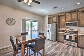 A modern kitchen with wooden cabinets, stainless steel appliances, and a dining area with a glass table and chairs.