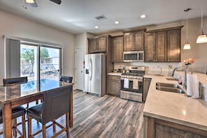 A modern kitchen with wooden cabinets, stainless steel appliances, and a marble countertop.
