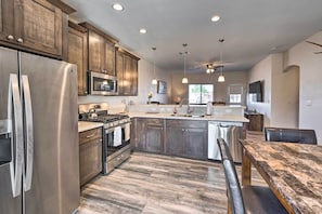 A modern kitchen with wooden cabinets, stainless steel appliances, and a marble countertop.