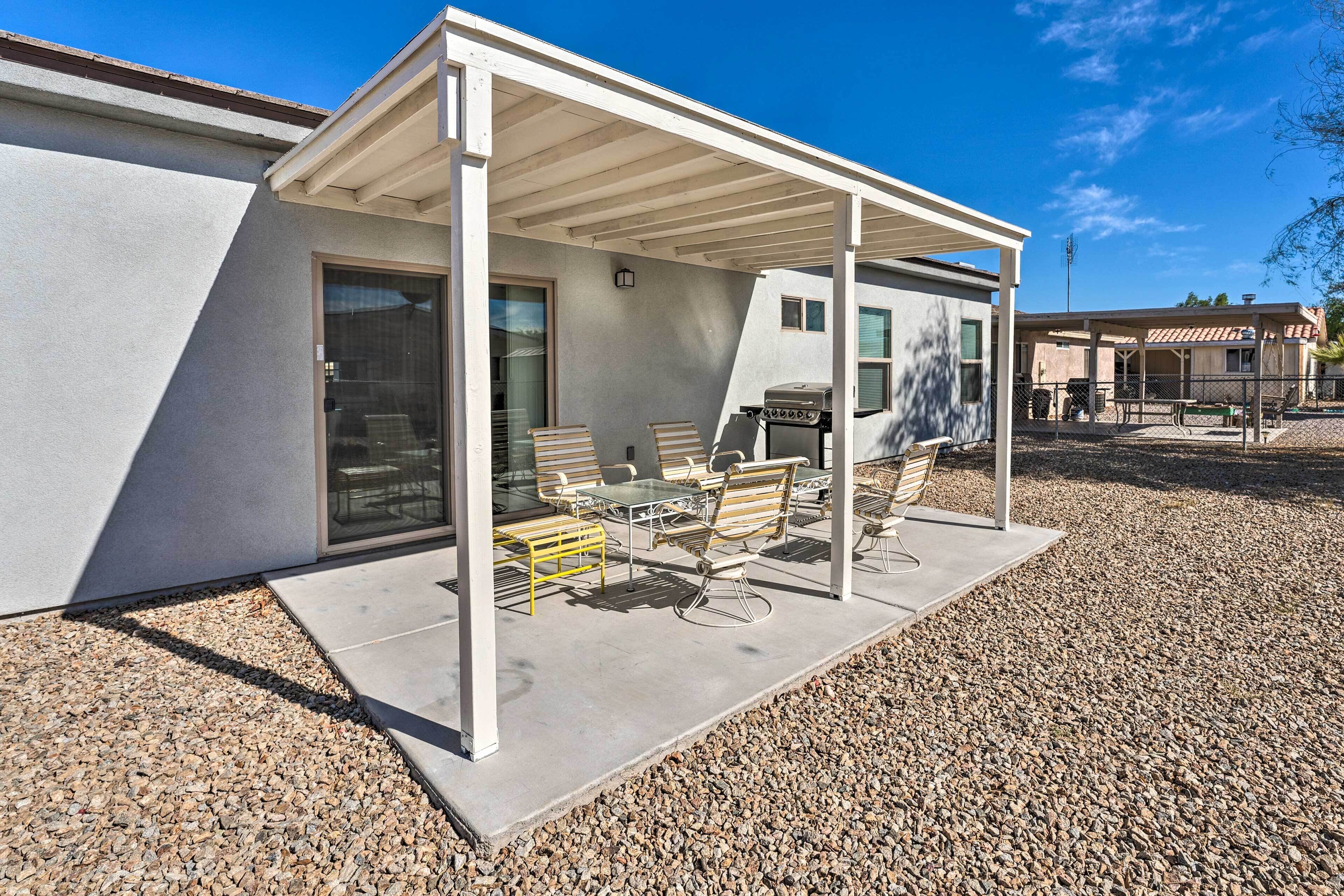A covered patio with outdoor furniture, a grill, and a view of a residential area.
