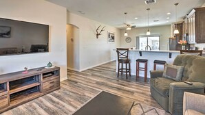 Un salon spacieux doté d’un grand téléviseur à écran plat, d’un meuble de rangement en bois et d’un canapé d’angle.